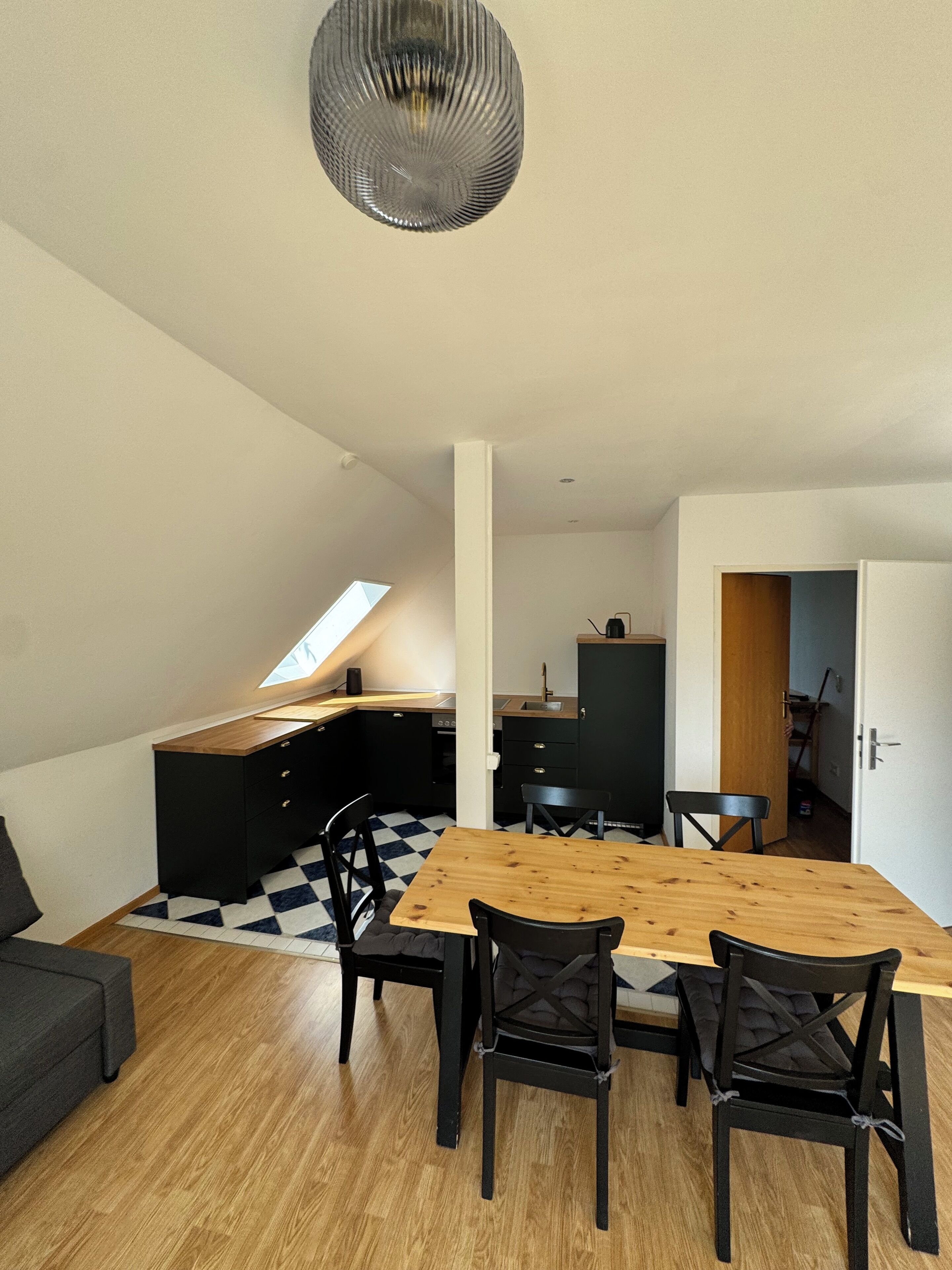 Een moderne keuken met zwarte kastjes, een houten eettafel en zwarte stoelen.