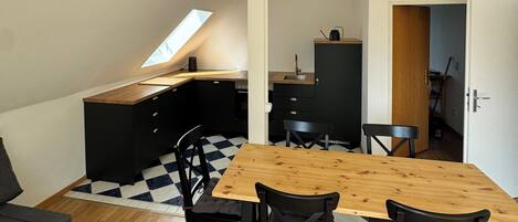 Een moderne keuken met zwarte kastjes, een houten eettafel en zwarte stoelen.