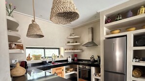 Uma cozinha moderna com ilha central, eletrodomésticos de aço inoxidável e luminárias pendentes de fibra trançada.