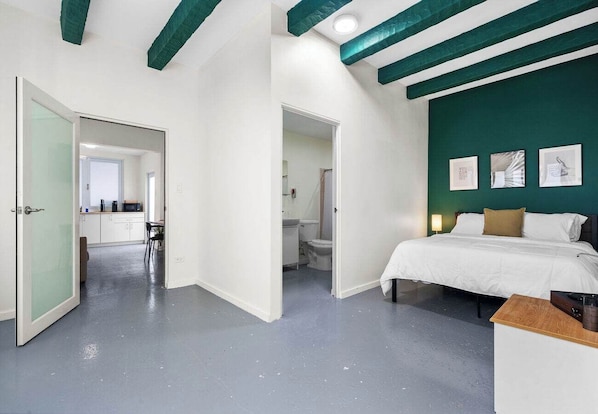 Una habitación de hotel moderna con una cama grande, un escritorio y una pared verde de acento.