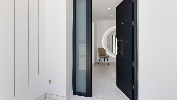Un interior moderno con una puerta de cristal que da a una zona de estar circular.