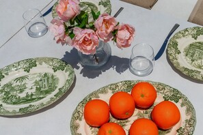 A table set with green and white patterned plates, a vase with pink flowers, and a plate of oranges. - Villa Monica in Alhaurin de la Torre (Alhaurin de la Torre)