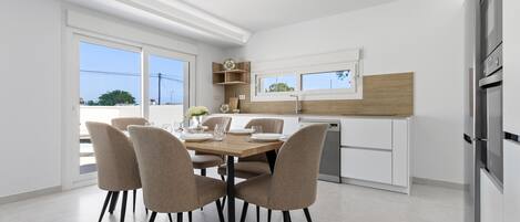 A modern kitchen with white cabinetry, a wooden dining table, and four chairs.