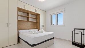 Un dormitorio moderno con cama, estanterías empotradas de madera, una ventana y una mesita de noche negra.