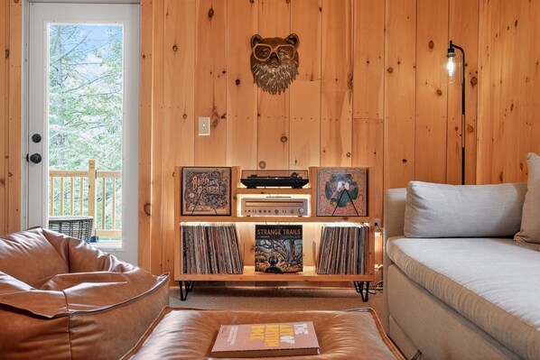 Una habitación acogedora con una pared de madera, una decoración con cabeza de oso, un tocadiscos y un sofá.