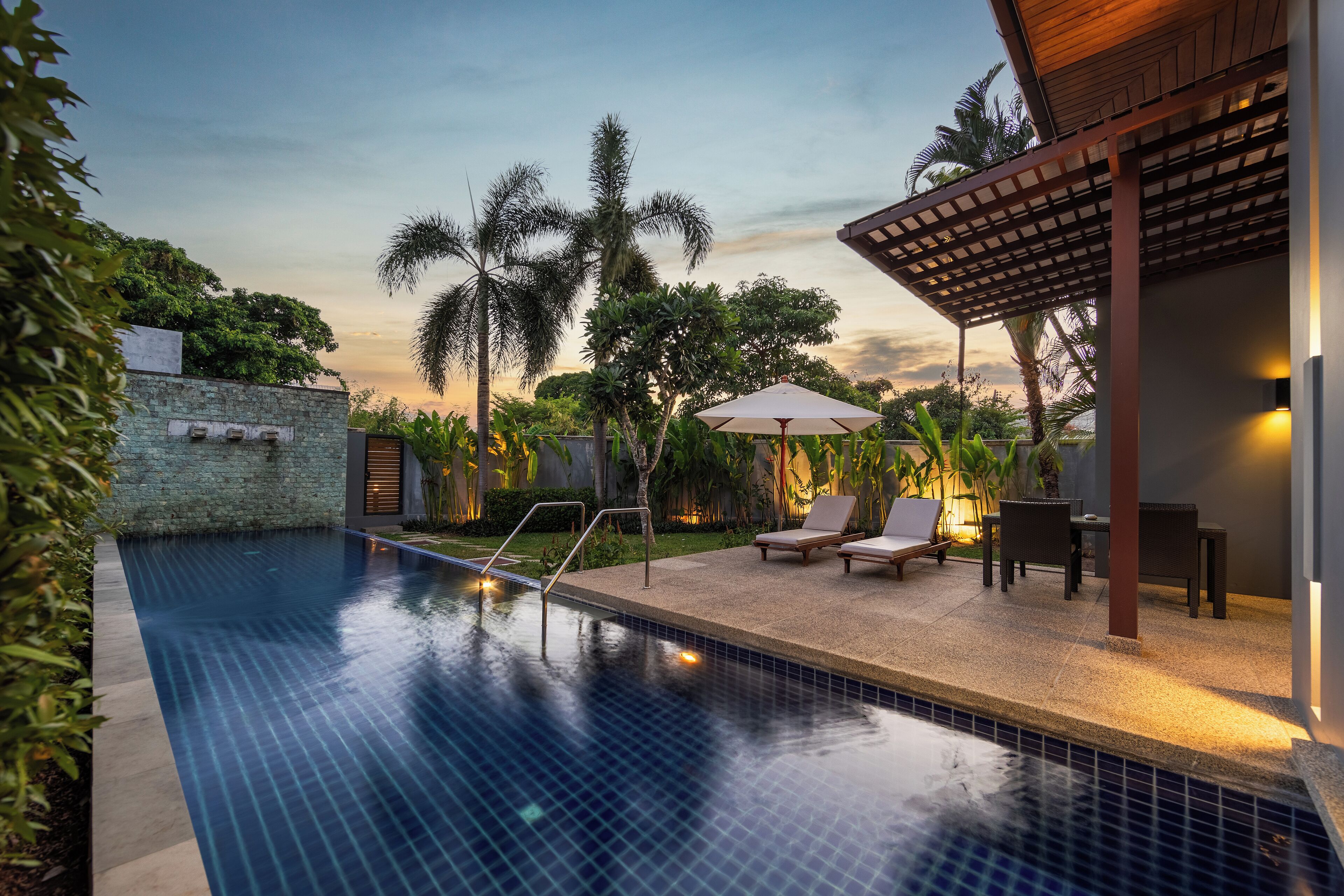 A swimming pool with a tiled edge, surrounded by lounge chairs and a pergola.