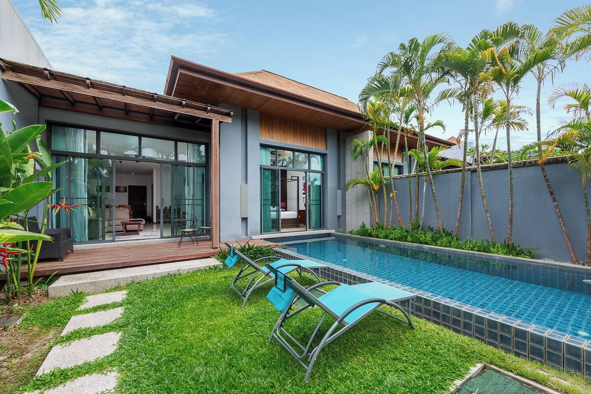 A modern house with a swimming pool, glass doors, and tropical plants.