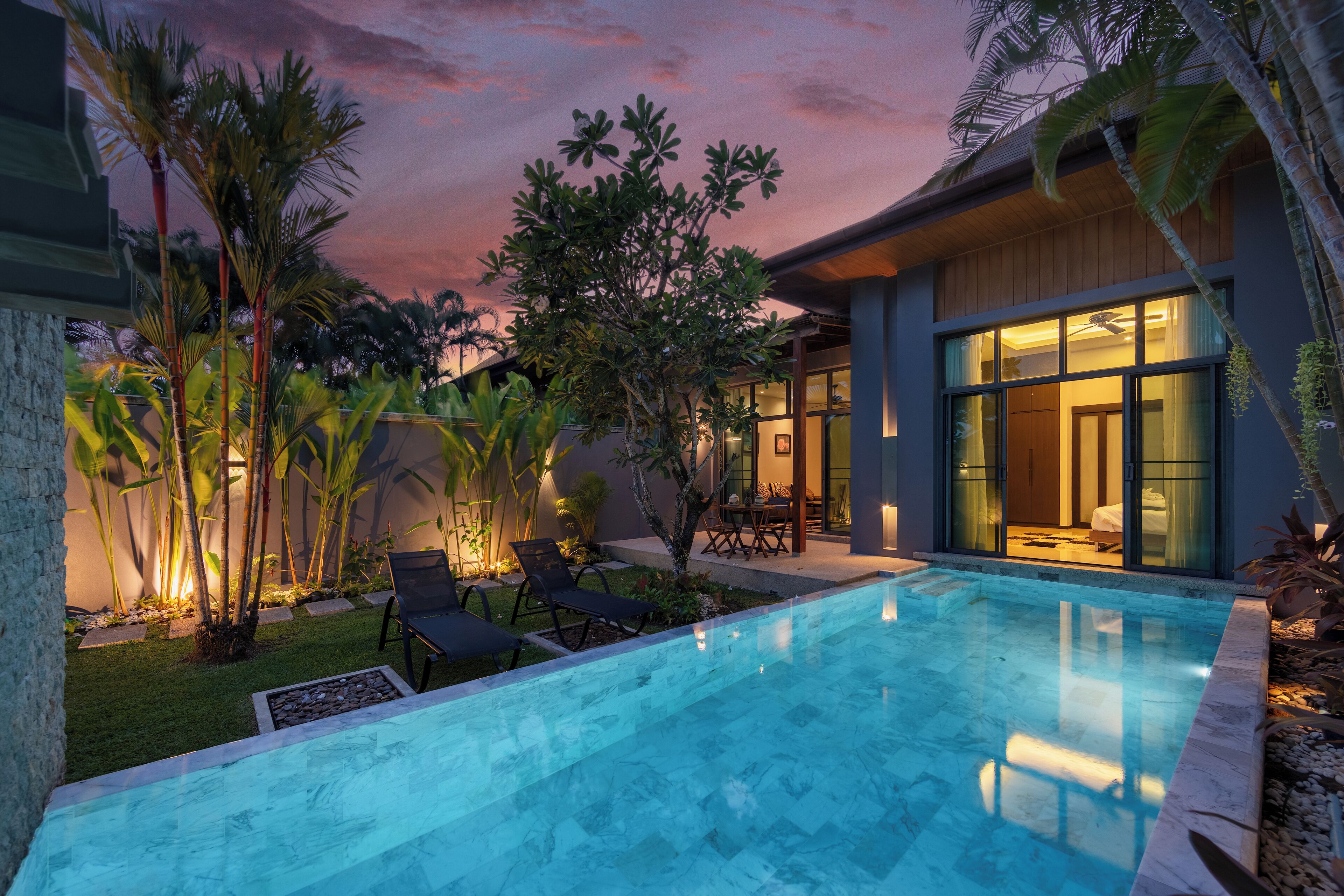 A modern house with a swimming pool, outdoor seating, and lush greenery.