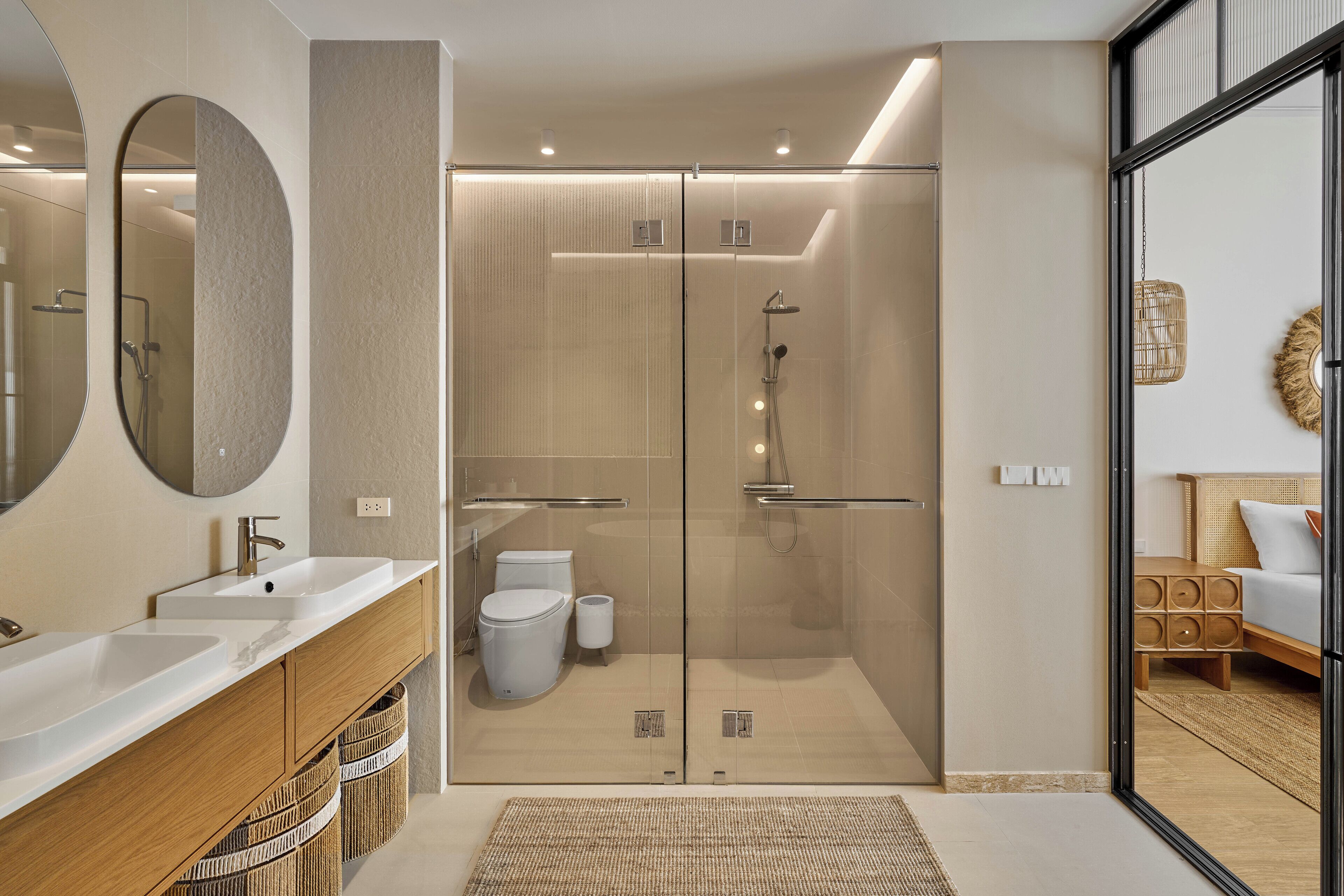 A modern bathroom with a glass-enclosed shower, a large mirror, and a wooden vanity.