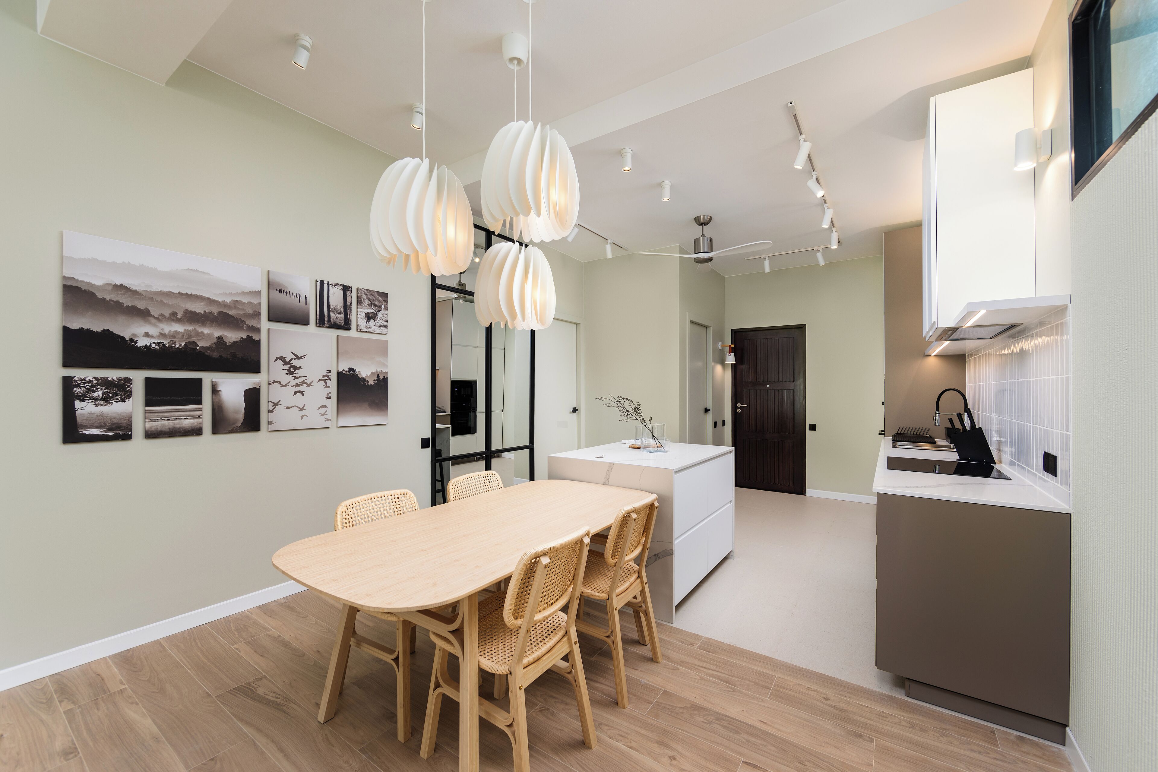 A modern kitchen with a built-in oven, a dining area with a wooden table and chairs, and a kitchen island.