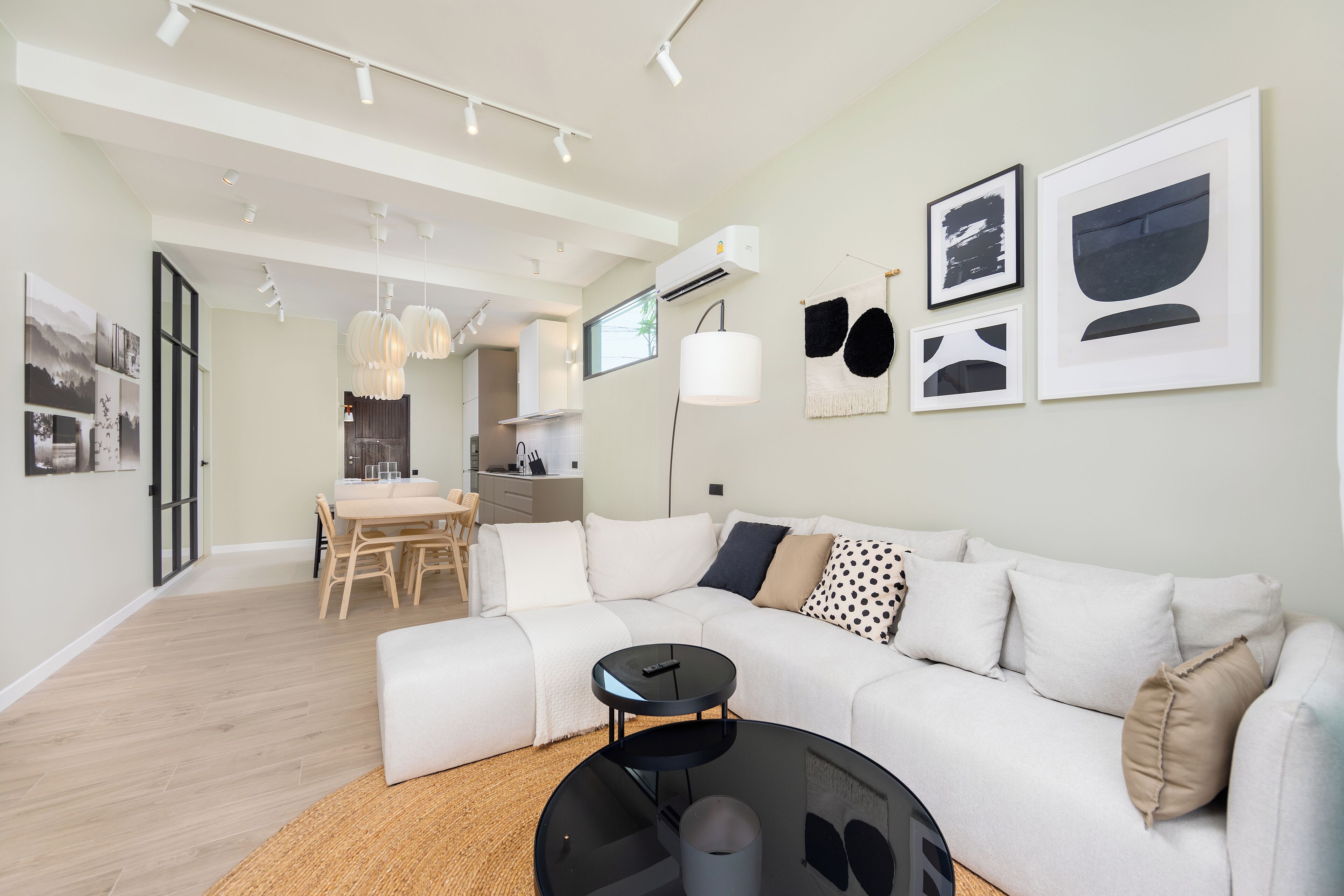 A modern living room with a sectional sofa, a round coffee table, and a dining area with a table and chairs.