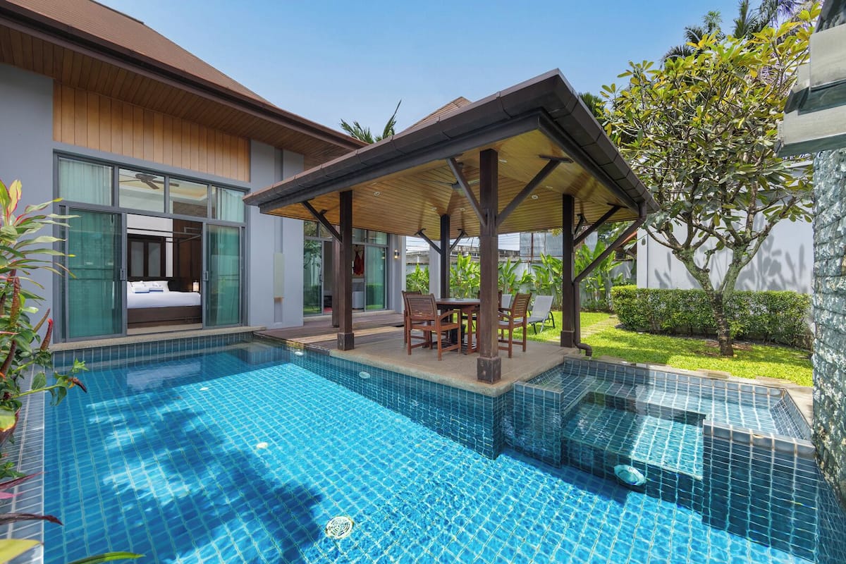 A modern hotel with a swimming pool, outdoor seating, and a covered patio area.