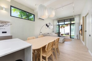 Un interior moderno con comedor, sofá, televisor y ventana grande.