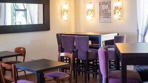 A dining area with tables and chairs, wall-mounted light fixtures, and framed pictures on the wall. - The Raceby Hotel, Doncaster (South Yorkshire), Part of the AG Collection (Doncaster)