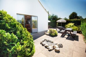 A modern outdoor patio with a fire pit, picnic tables, and a glass door leading to a room. - The Raceby Hotel, Doncaster (South Yorkshire), Part of the AG Collection (Doncaster)