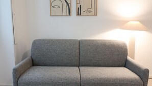 Un sofá gris en una habitación con una lámpara y arte abstracto en la pared.