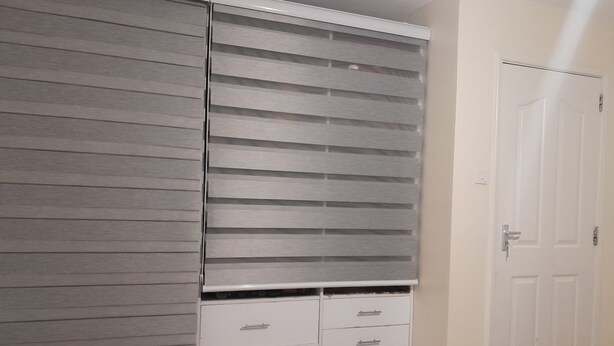 Una habitación con puerta corredera, una puerta blanca y un mueble blanco con cajones.