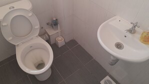 Un baño con inodoro, lavabo y escobilla.