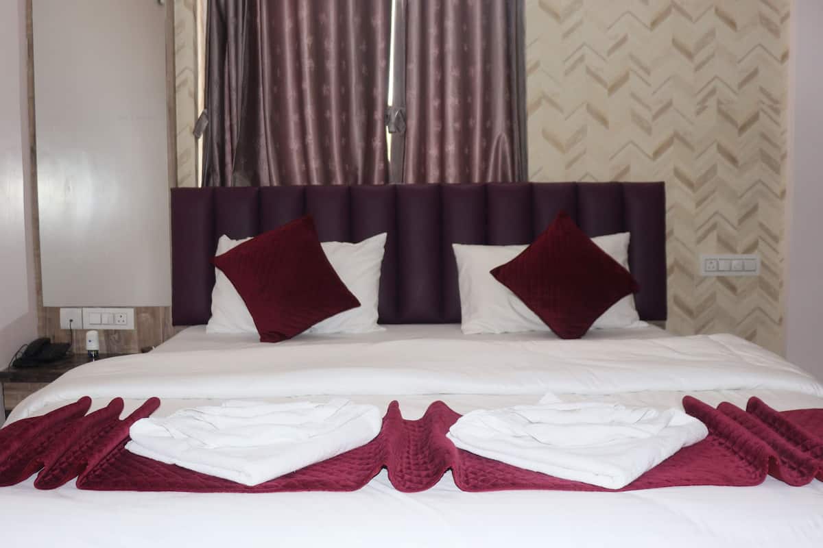 Une chambre d’hôtel avec un lit, une table de chevet et une fenêtre avec des rideaux.