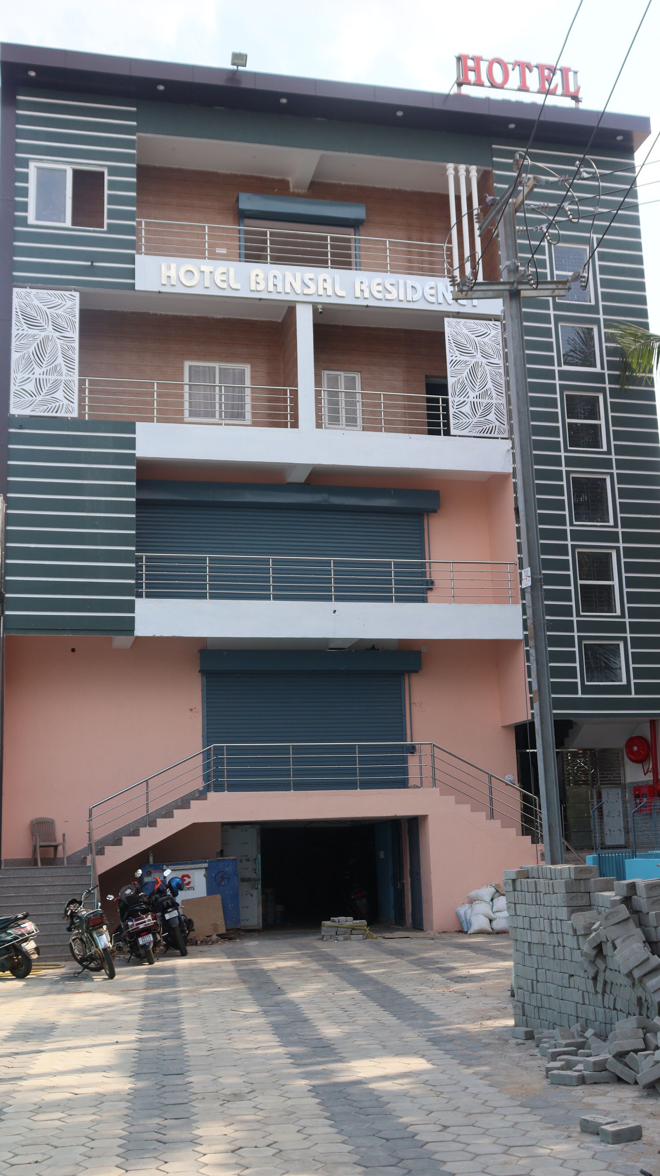 A multi-story building with a sign indicating it is a hotel. There are balconies on the upper floors, and a staircase leading to the entrance.