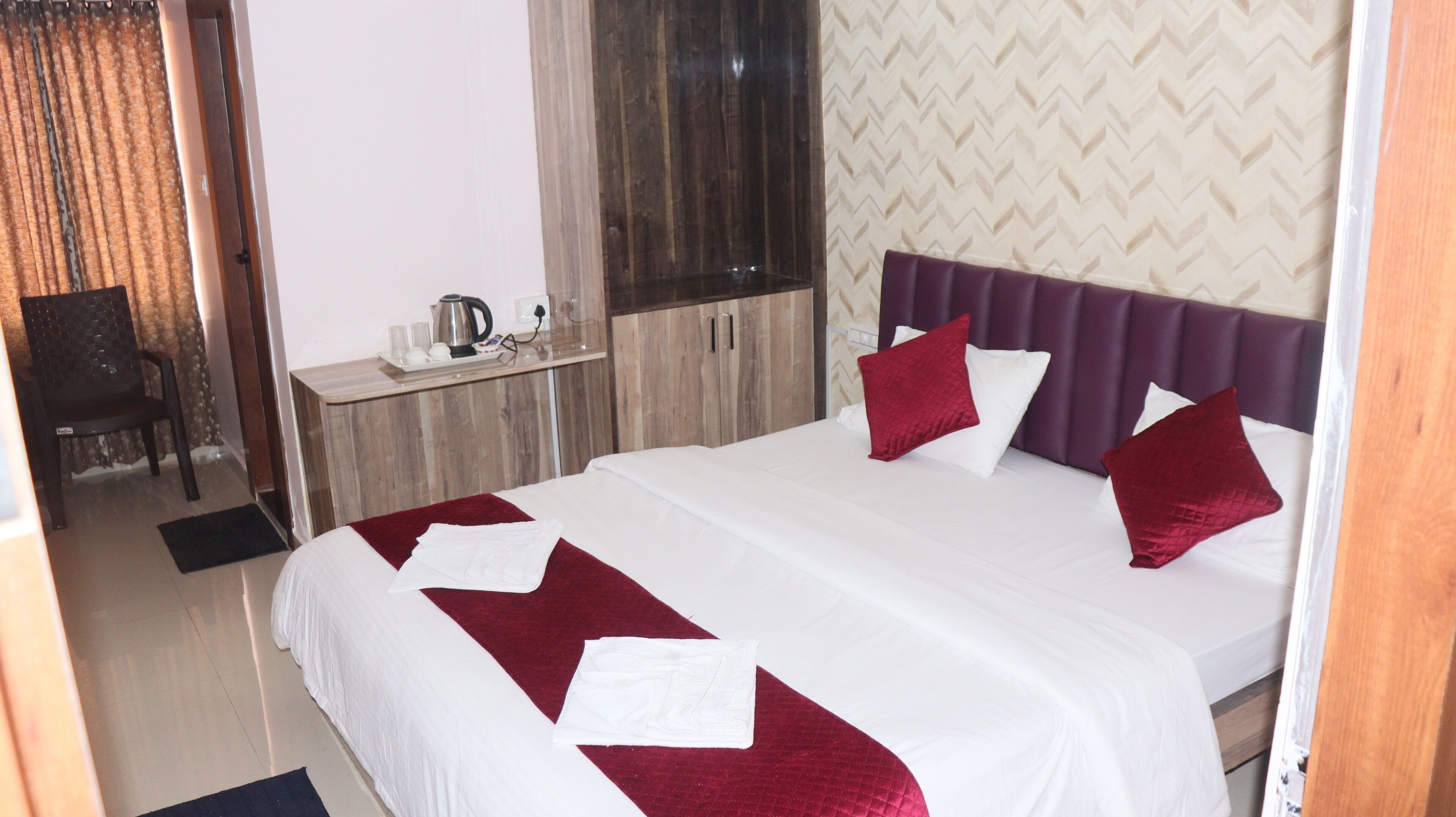 A hotel room with a bed, a desk, a chair, and a window with curtains.