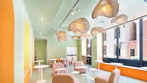 A brightly lit room with green walls, multiple seating areas, and large windows offering views of the outside. - Boavista 83 Hostel Lisbon (Lisbon)
