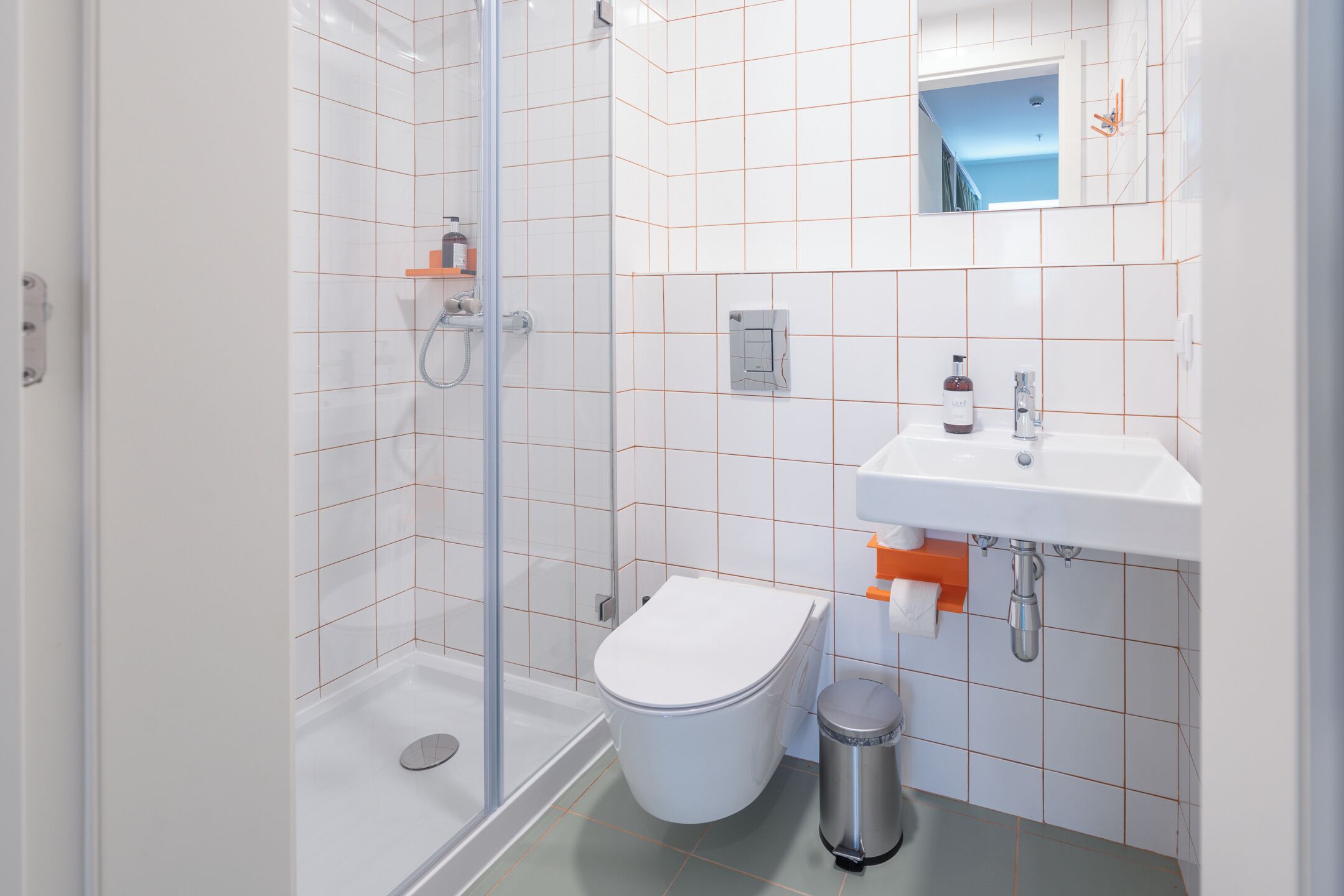 A modern bathroom with a glass shower enclosure, a white toilet, and a sink with a mirror above it.