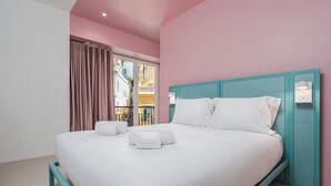 A neatly made bed with white linens and pillows, a teal headboard, and a window with curtains. - Boavista 83 Hostel Lisbon (Lisbon)