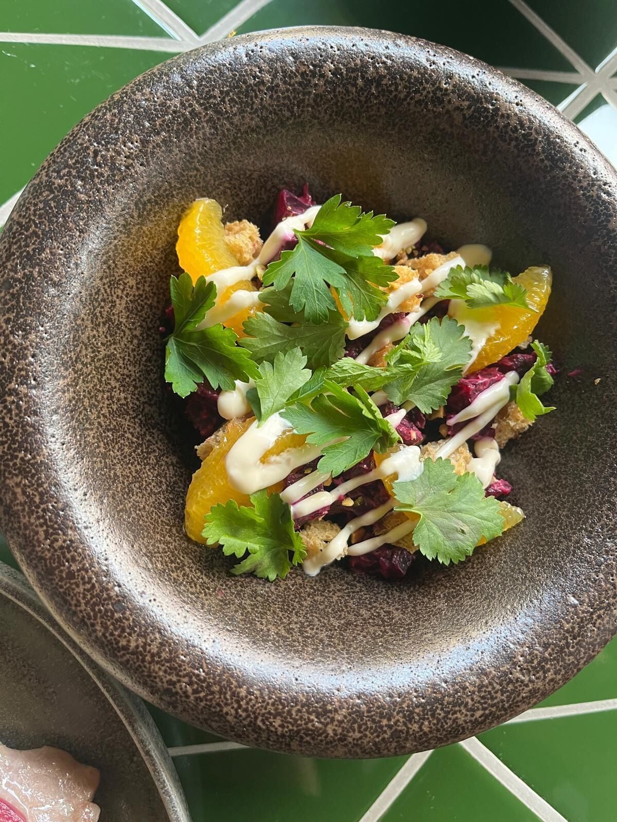 Une salade composée de quartiers d’orange, de chou rouge et de persil, servie dans un saladier texturé.