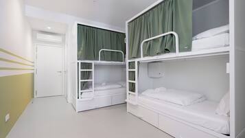 Una habitación con literas, una puerta blanca y una cortina verde.