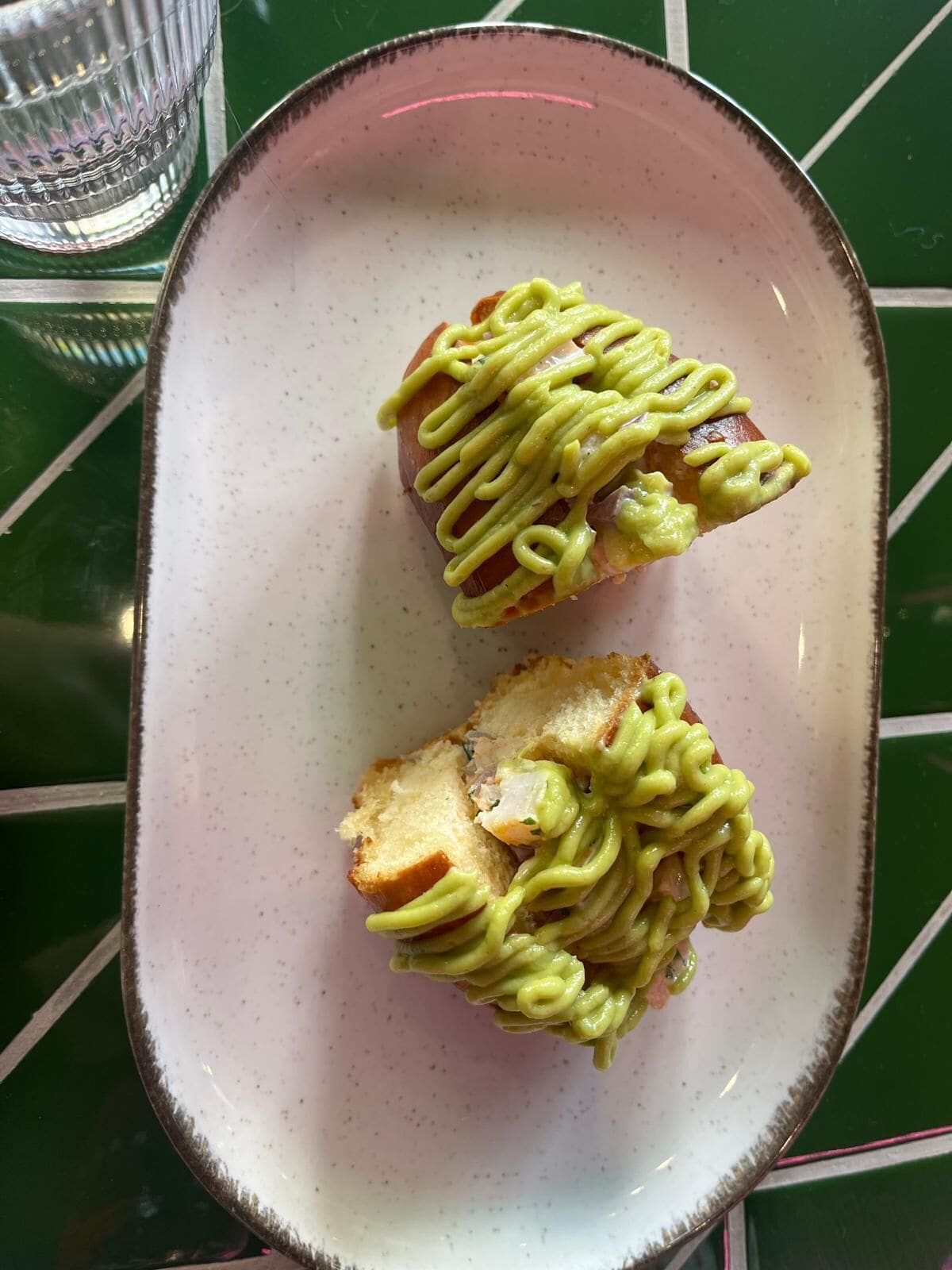 A plate with two pieces of bread topped with green sauce, on a green table.