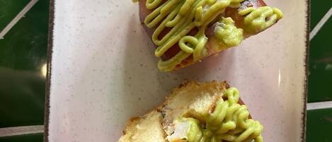 A plate with two pieces of bread topped with green sauce, on a green table.