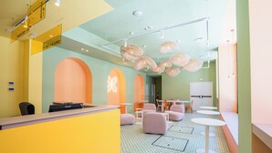 A reception area with a yellow counter, seating, and a patterned floor. - Boavista 83 Hostel Lisbon (Lisbon)