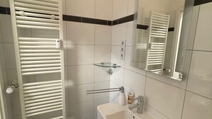 A bathroom with a white sink, mirror, and towel rack. - Superior Apartment: City location Museums Castles Phantasialand shuttle on the doorstep (Brühl)