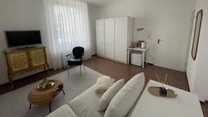 A modern hotel room with a white sofa, a small coffee table, a television, a wardrobe, and a desk with a chair. - Superior Apartment: City location Museums Castles Phantasialand shuttle on the doorstep (Brühl)