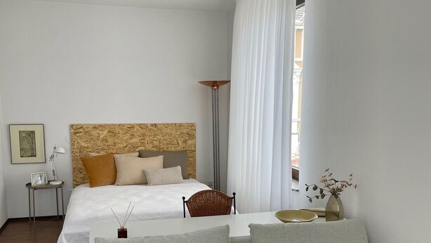A modern hotel room with a large bed, a grey sofa, a small table with a vase, and a floor lamp. - Superior Apartment: City location Museums Castles Phantasialand shuttle on the doorstep (Brühl)