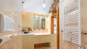 A bathroom with a sink, mirror, towel rack, and a shower area.