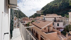 A residential area with buildings, a balcony, and a view of a hillside.