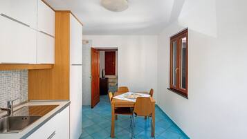 Una cocina compacta con lavamanos, armarios de madera y una zona de comedor con mesa y sillas.