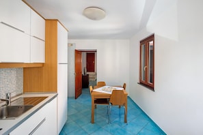 Une cuisine compacte équipée d’un évier, de meubles en bois et d’un coin repas avec une table et des chaises.