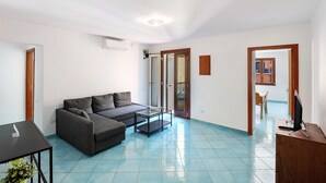 A living room with a sofa, coffee table, and TV stand. - Apartment 'Ce Tour - Casa Cetara Centro' with Balcony, Wi-Fi and Air Conditioning (Cetara)