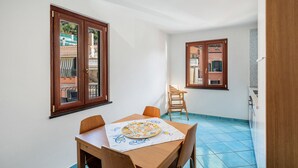 A small dining area with a table, chairs, and a pizza on a placemat. - Apartment 'Ce Tour - Casa Cetara Centro' with Balcony, Wi-Fi and Air Conditioning (Cetara)