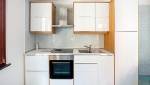 A compact kitchen with white cabinets, a stainless steel sink, and a built-in oven. - Apartment 'Ce Tour - Casa Cetara Centro' with Balcony, Wi-Fi and Air Conditioning (Cetara)