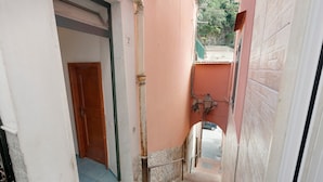 A narrow hallway with a wooden door, a metal railing, and a small window. - Apartment 'Ce Tour - Casa Cetara Centro 1' with Private Terrace, Wi-Fi and Air Conditioning (Cetara)
