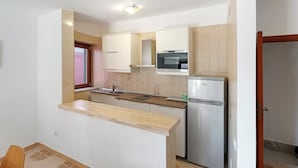 A compact kitchen with a built-in oven, a refrigerator, and a window with a view. - Apartment 'Ce Tour - Casa Cetara Centro 1' with Private Terrace, Wi-Fi and Air Conditioning (Cetara)