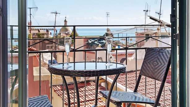 Ein Balkon mit Tisch und Stühlen mit Blick auf eine Stadtlandschaft mit Gebäuden und Antennen.