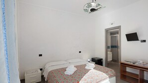 Ein Schlafzimmer mit Bett, Nachttisch und Schreibtisch mit Stuhl.