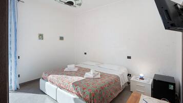 Una habitación de hotel con una cama, una mesita de noche y un pequeño armario negro.
