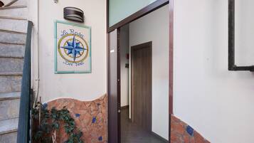 A hallway with a tiled wall, a wooden door, and a wall-mounted compass sign.