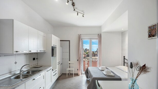 Una cocina moderna con armarios blancos, un lavamanos doble y una zona de comedor con mesa y sillas.